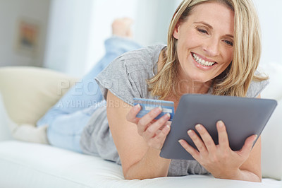 Buy stock photo Shot of an attractive mature woman using her tablet to do some online shopping