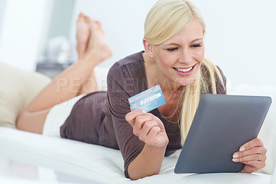 Buy stock photo Shot of a beautiful woman doing some online shopping at home using her digital tablet