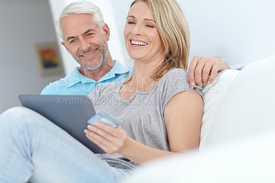 Buy stock photo Shot of a mature couple sitting with their tablet and doing some online shopping at home