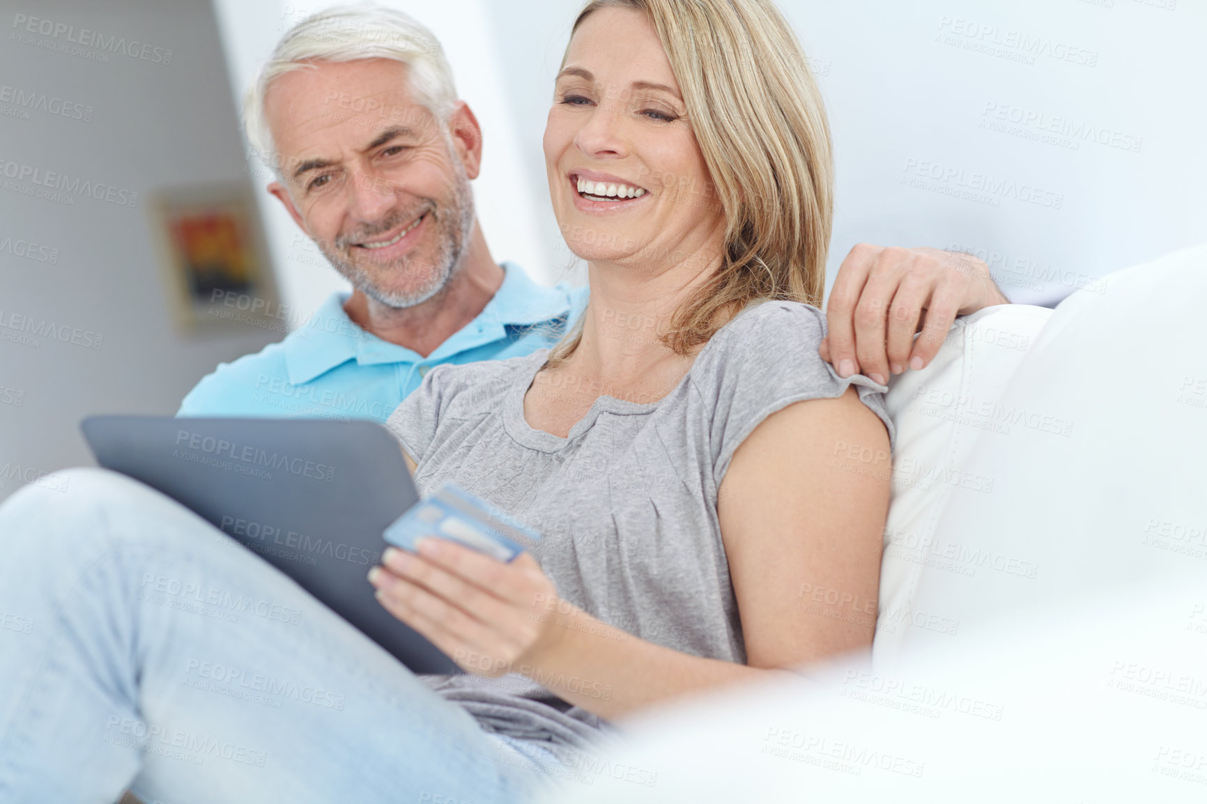 Buy stock photo Shot of a mature couple sitting with their tablet and doing some online shopping at home