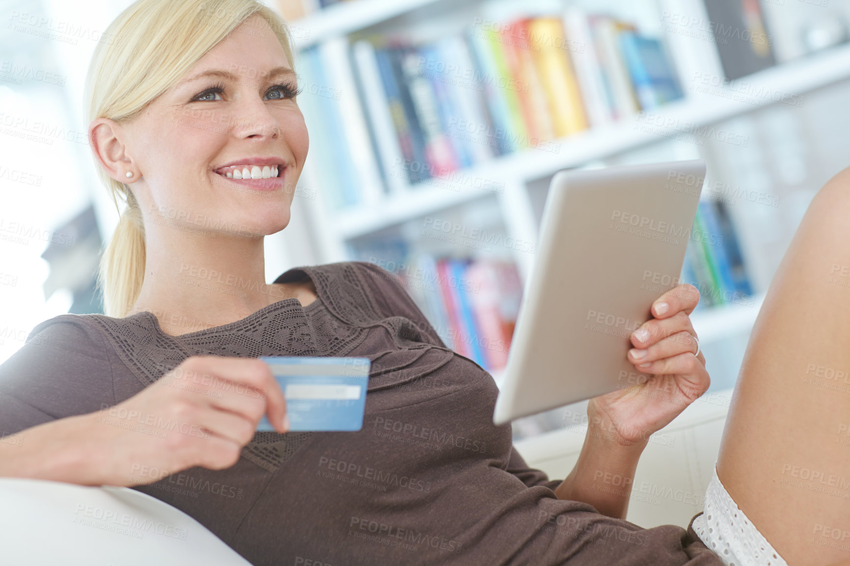 Buy stock photo Shot of a beautiful woman doing some online shopping at home using her digital tablet