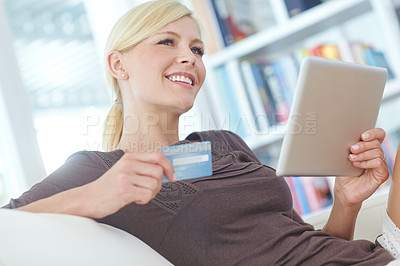 Buy stock photo Shot of a beautiful woman doing some online shopping at home using her digital tablet