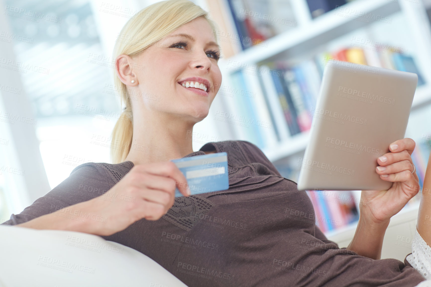 Buy stock photo Shot of a beautiful woman doing some online shopping at home using her digital tablet