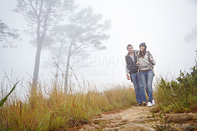 Buy stock photo Shot of a young couple hiking along a trail in foggy weather