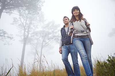 Buy stock photo Shot of a young couple hiking along a trail in foggy weather