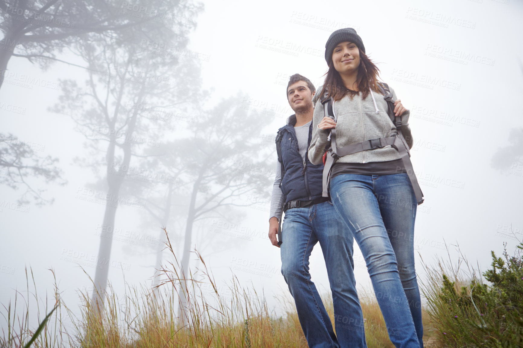 Buy stock photo Walking, couple and hiking outdoor for holiday, vacation trip and adventure with low angle in woods. Forest, happy man and woman trekking for tourism, fitness and travel to explore nature with fog