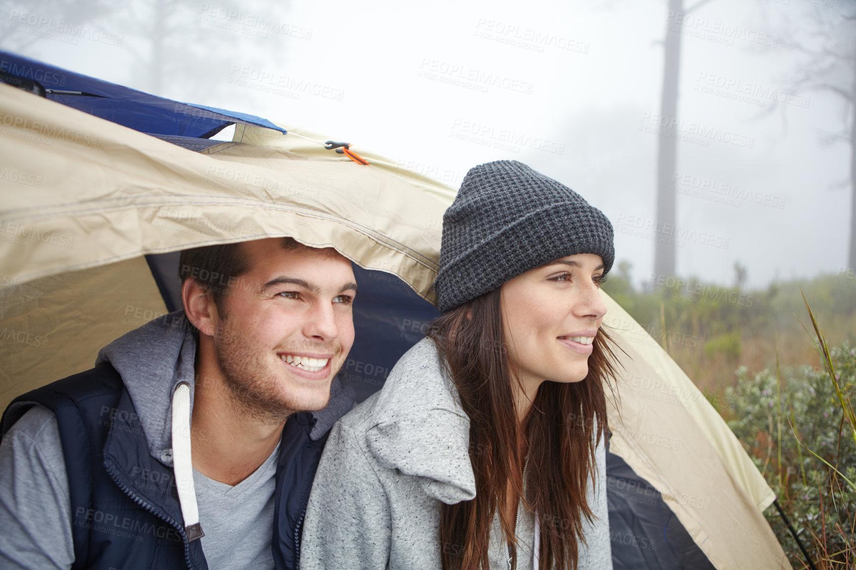 Buy stock photo Shot of a young couple sitting inside their tent while on a camping trip