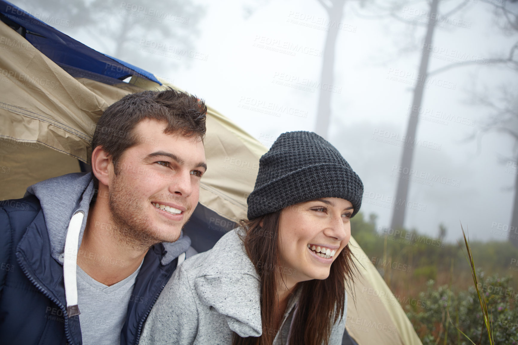 Buy stock photo Shot of a young couple sitting inside their tent while on a camping trip