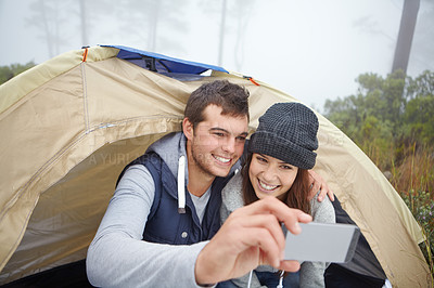 Buy stock photo Shot of a young couple taking a photo of themselves while on a camping trip