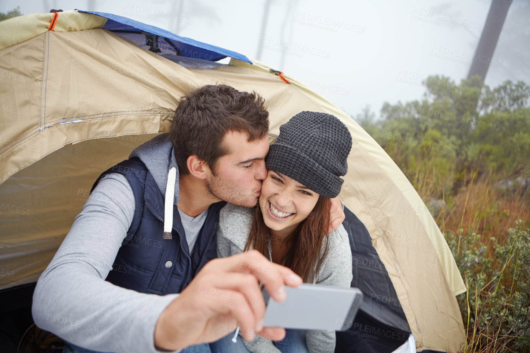 Buy stock photo Shot of a young couple taking a photo of themselves while on a camping trip