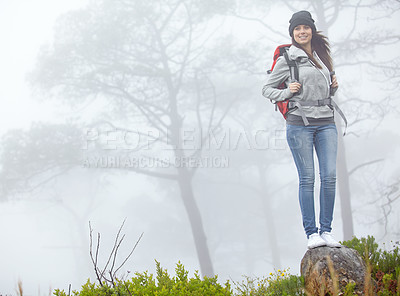 Buy stock photo Shot of a beautiful young woman standing on a rock while out hiking