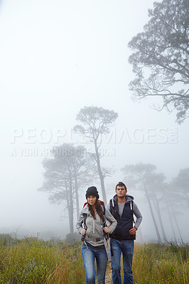 Buy stock photo Shot of a young couple hiking through nature