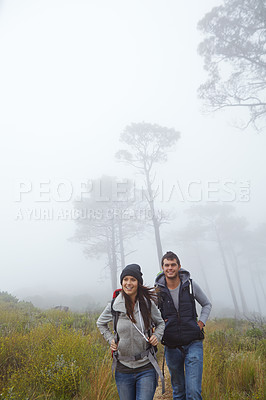 Buy stock photo Shot of a young couple hiking through nature