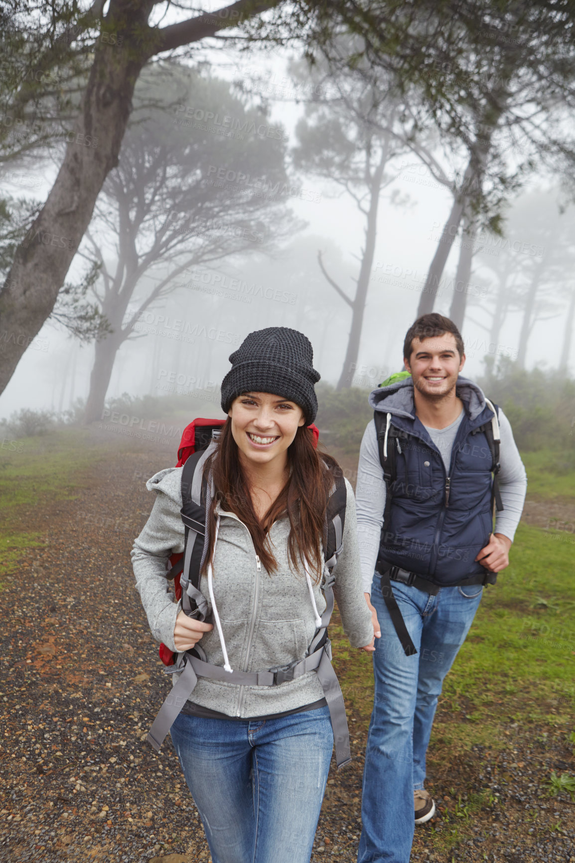 Buy stock photo Shot of a young couple hiking along a forest trail