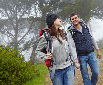 Buy stock photo Shot of a young couple hiking along a forest trail