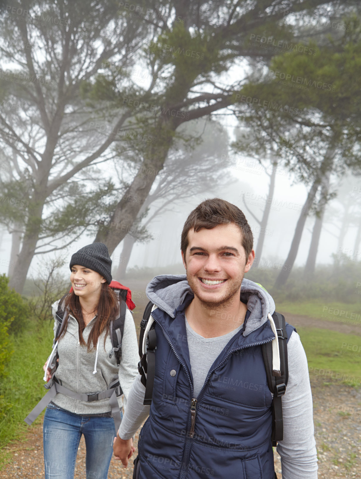 Buy stock photo Shot of a handsome young man hiking through a forest with his girlfriend