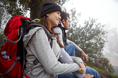 Buy stock photo Shot of a young couple sitting down for a rest while out hiking