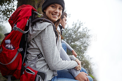 Buy stock photo Shot of a young couple sitting down for a rest while out hiking