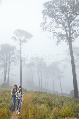 Buy stock photo Full length shot of a young couple hiking along a nature trail