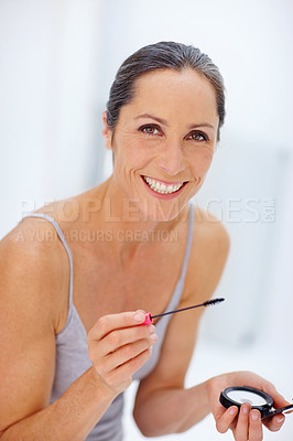 Buy stock photo Mature woman, makeup and happy with mascara on portrait  for makeover on white background in France. Female person, smile and satisfied with compact mirror for eyelashes, beauty and glow in cosmetics