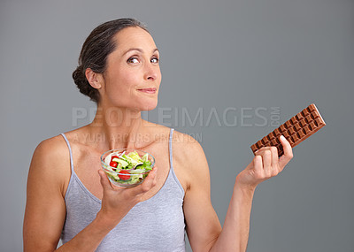 Buy stock photo Mature woman, portrait and salad bowl with chocolate for diet, pick or choice in studio on a gray background. Female person, nutritionist or model with smile for mix vegetables, dessert or decision