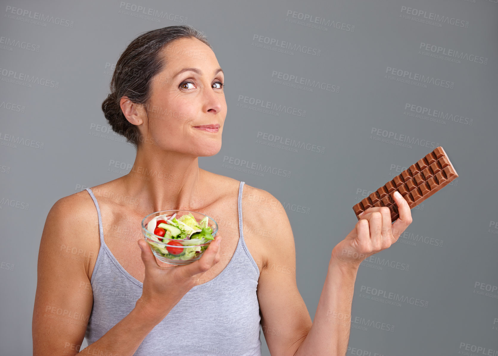 Buy stock photo Mature woman, portrait and salad bowl with chocolate for diet, pick or choice in studio on a gray background. Female person, nutritionist or model with smile for mix vegetables, dessert or decision