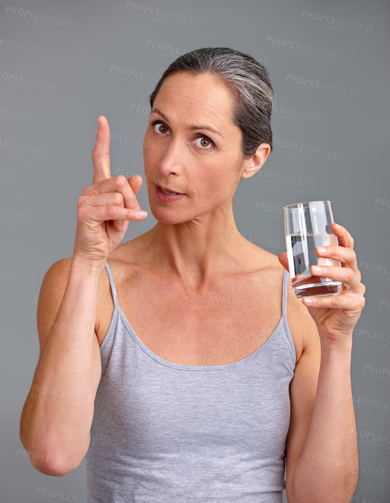 Buy stock photo Woman, portrait and water with glass for hydration, diet or beverage in studio on a gray background. Mature, female person or model with tips or vitamins for healthy digestion or mineral liquid