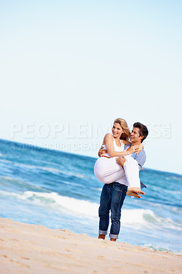 Buy stock photo Shot of a happy young couple enjoying a romantic day on the beach