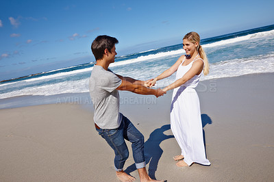 Buy stock photo Shot of a happy young couple enjoying a playful moment at the beach