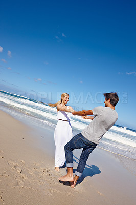 Buy stock photo Shot of a happy young couple enjoying a playful moment at the beach