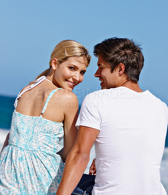 Buy stock photo Rearview shot of a loving couple sitting together at the water's edge