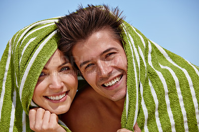 Buy stock photo Portrait of a playful young couple covering themselves with a towel