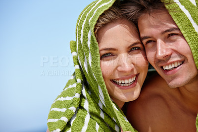 Buy stock photo Portrait of a playful young couple covering themselves with a towel