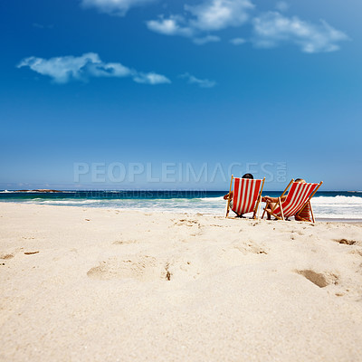 Buy stock photo Rearview shot of an affectionate couple reclining on their deck chairs at the water's edge