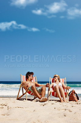 Buy stock photo Couple, relax and holding hands on beach for travel, bonding or tropical holiday with blue sky. Man, woman and tanning outdoor for fun trip, love and vacation with sunshine, chill and date on weekend