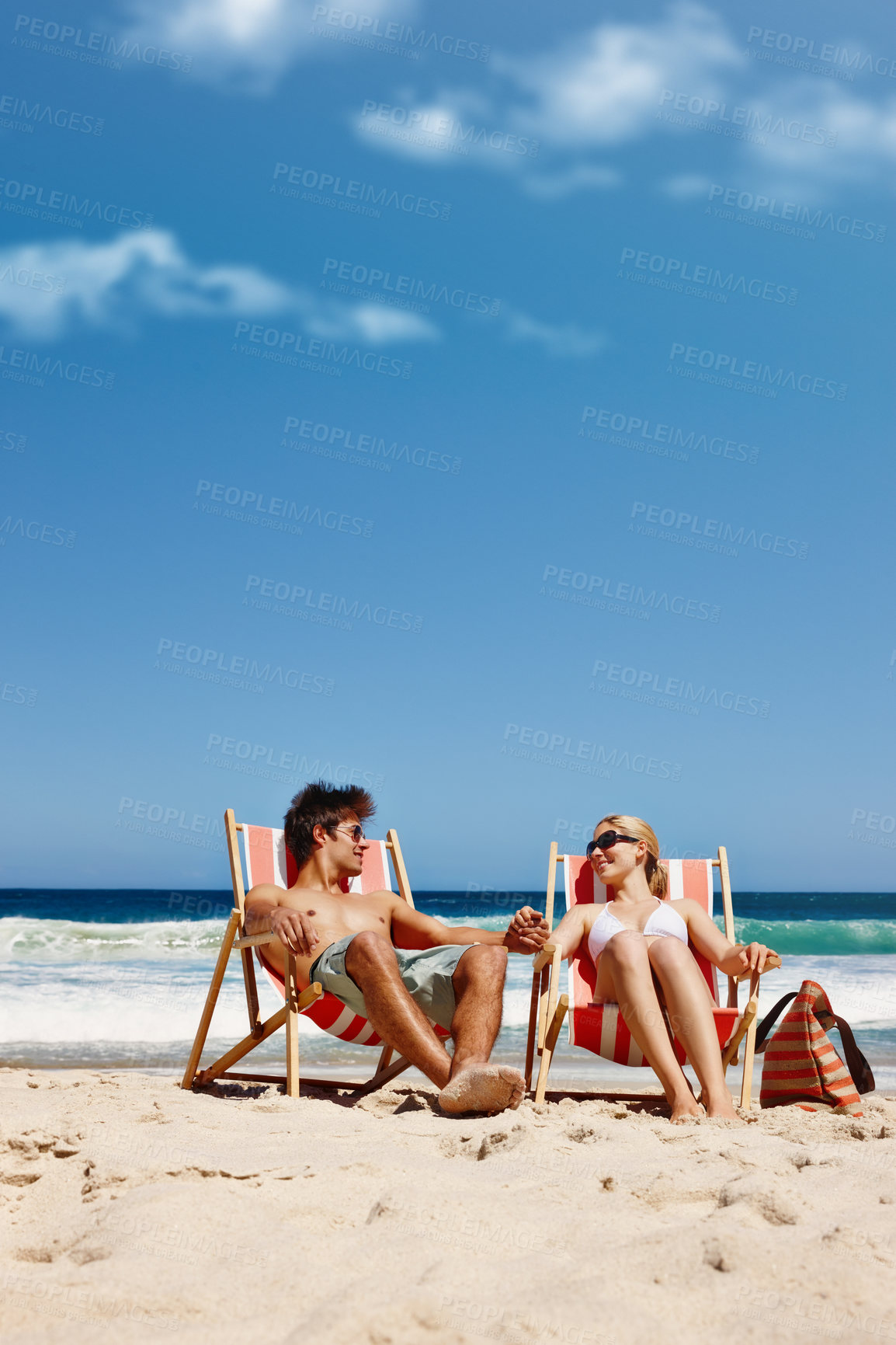 Buy stock photo Couple, relax and holding hands on beach for travel, bonding or tropical holiday with blue sky. Man, woman and tanning outdoor for fun trip, love and vacation with sunshine, chill and date on weekend