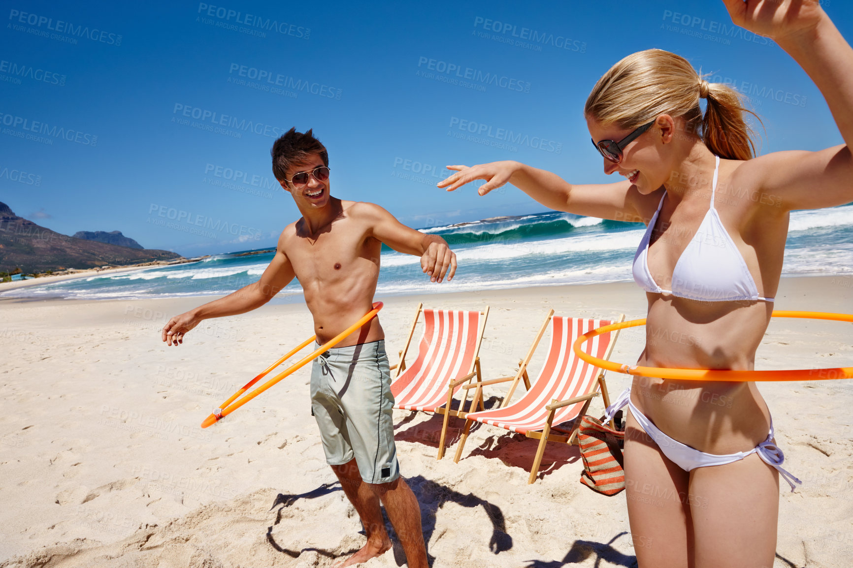 Buy stock photo Couple, plastic hoop and beach play by waves together for fun, holiday or bonding with core exercise in nature. Happy people, game and Miami ocean with vacation, adventure and travel with trip