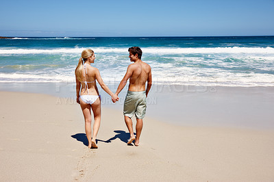 Buy stock photo Rearview shot of a happy young couple holding hands at the beach