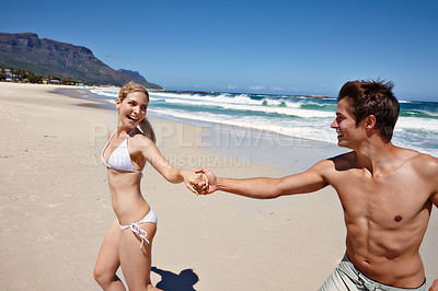 Buy stock photo Shot of a happy young couple enjoying a playful moment at the beach