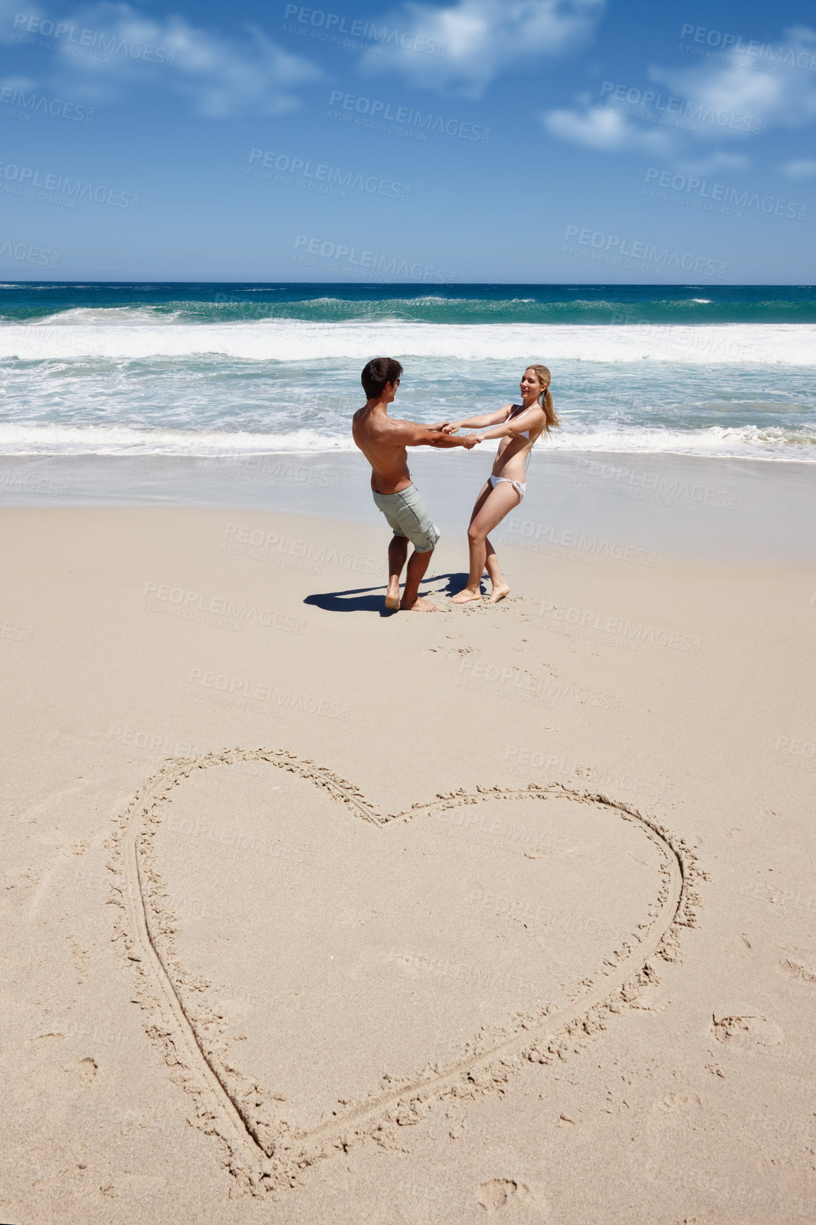 Buy stock photo Couple, playful and love at beach for bonding, travel and tropical holiday with heart on sand. Man, woman and romance outdoor for trip, draw and vacation with summer, relax and partner in Santorini