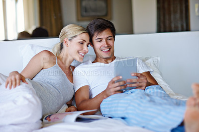 Buy stock photo Couple, happy and tablet on bed for relax, bonding and streaming movie with website, app and video. Man, woman and technology in home for relationship, love and social media with film subscription