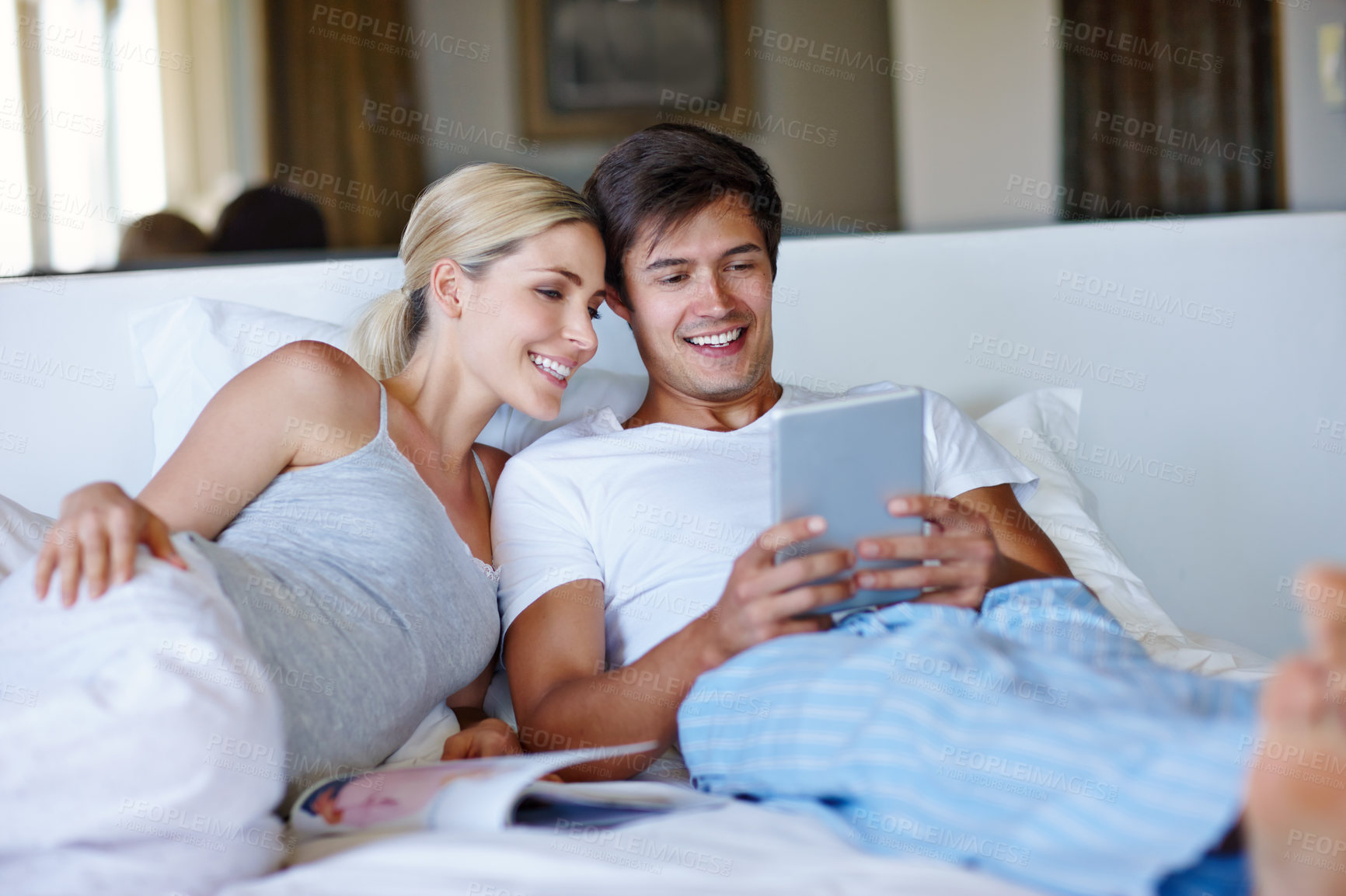 Buy stock photo Couple, happy and tablet on bed for relax, bonding and streaming movie with website, app and video. Man, woman and technology in home for relationship, love and social media with film subscription