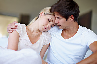 Buy stock photo Shot of a sad young woman being comforted by her husband in bed