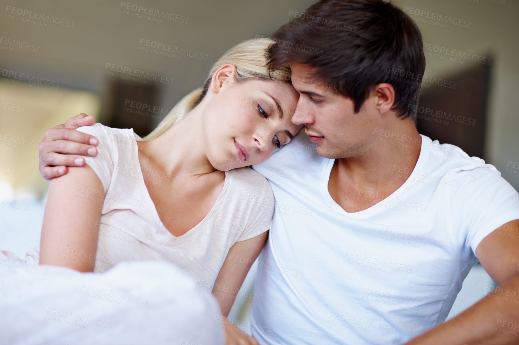 Buy stock photo Shot of a sad young woman being comforted by her husband in bed