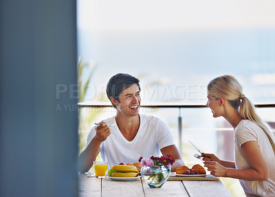 Buy stock photo Shot of a happy young couple eating breakfast together on the deck at home