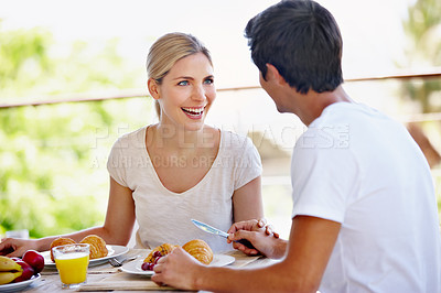 Buy stock photo Shot of a happy young couple eating breakfast together on the patio at home