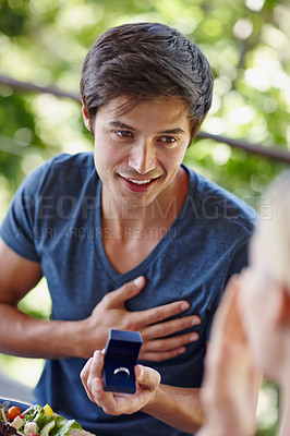 Buy stock photo Shot of a handsome young man proposing to his girlfriend with an engagement ring