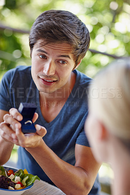 Buy stock photo Shot of a handsome young man proposing to his girlfriend with an engagement ring
