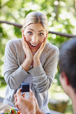 Buy stock photo Shot of a beautiful young woman looking surprised as her boyfriend is proposing