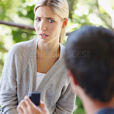 Buy stock photo Shot of a beautiful young woman looking uncertain as her boyfriend is proposing